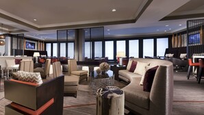 A spacious lobby with a modern design, featuring a mix of seating areas, a reception desk, and large windows offering views. - Hyatt Regency Long Island (Hauppauge)