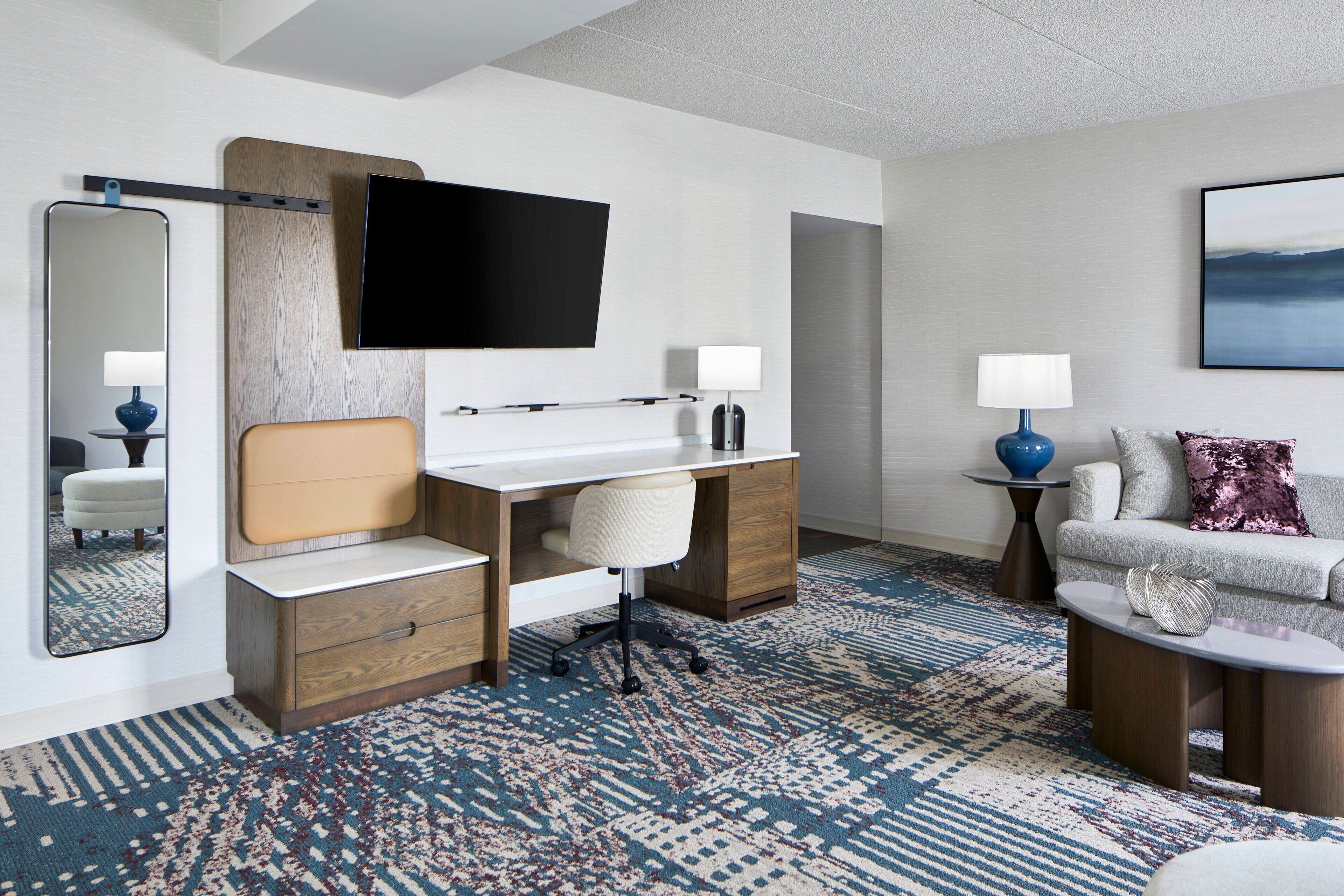 Una habitación de hotel moderna con escritorio, silla y sofá.