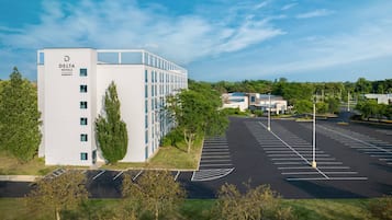 A modern Delta Hotels Marriott building with a parking lot and surrounding greenery.