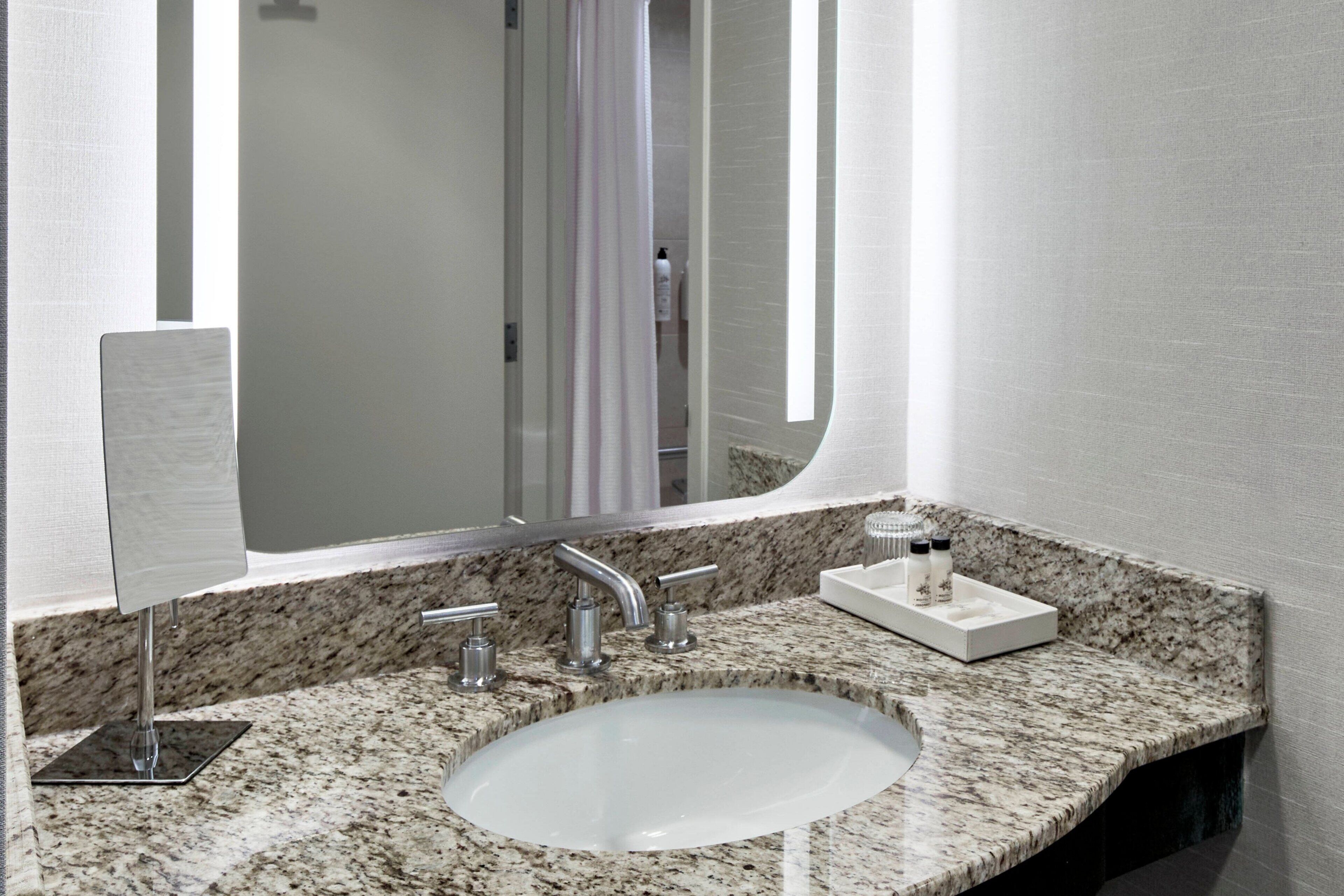 A bathroom with a granite countertop, a white sink, and a mirror.