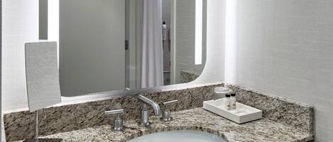 Un baño con encimera de granito, un lavamanos blanco y un espejo.