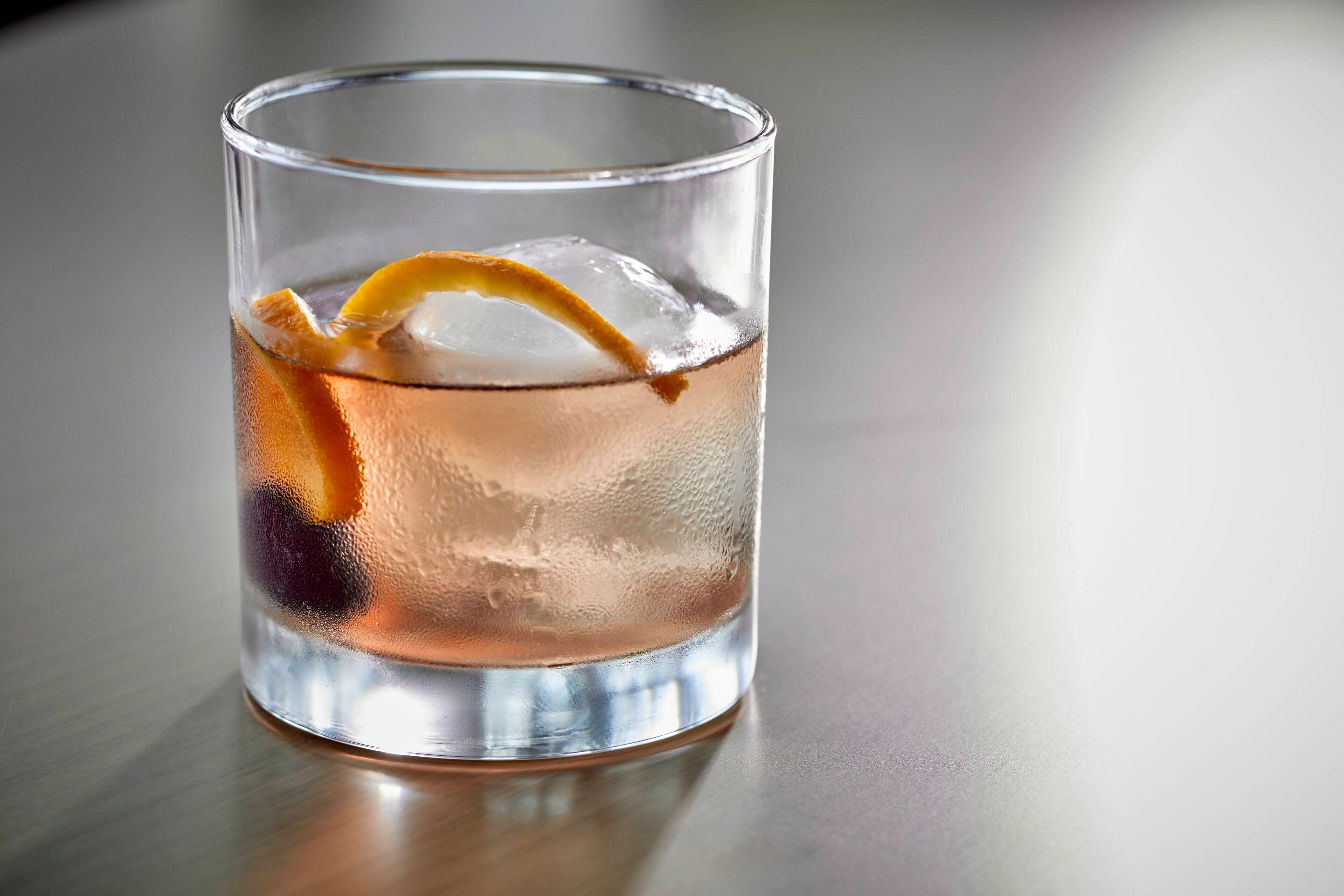Ein klares Glas mit Eiswürfeln und einer Orangenscheibe.