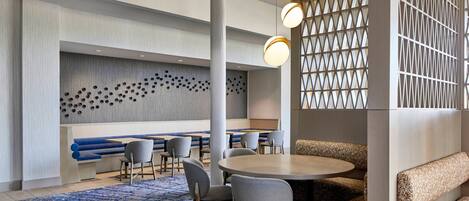 A modern hotel lobby with a seating area, a patterned wall, and a blue carpet.