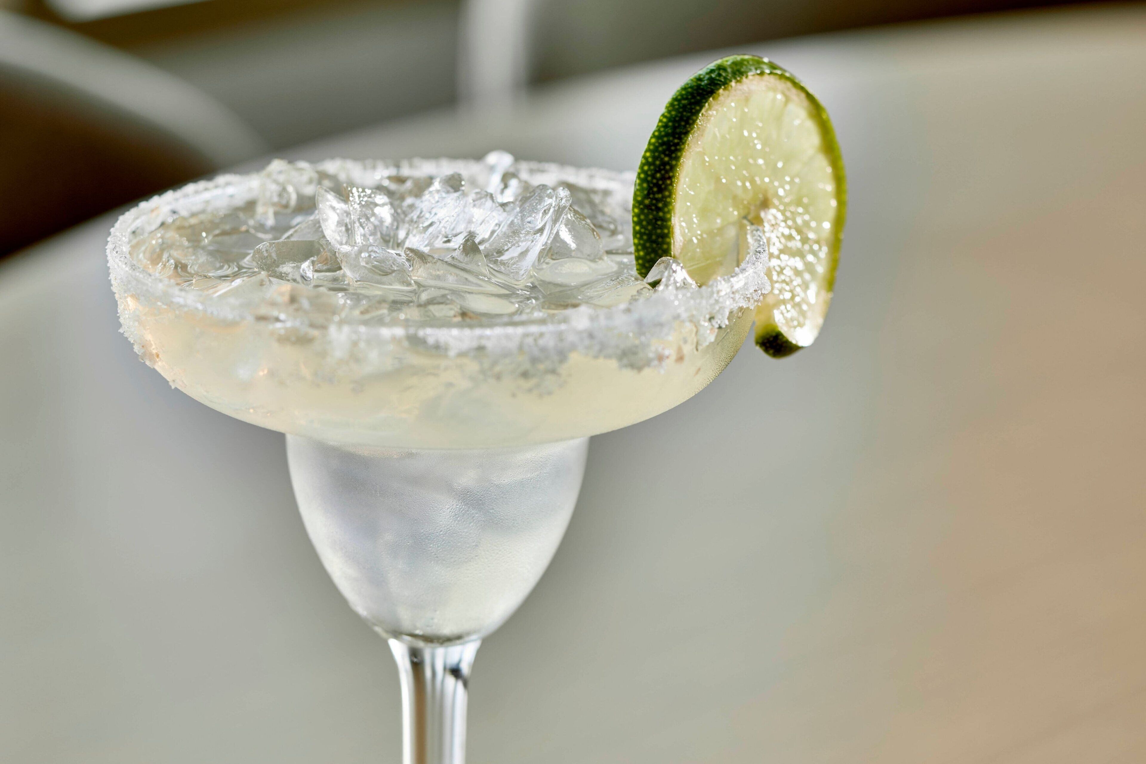 Un cocktail margarita servi avec des glaçons et décoré d’une tranche de citron vert dans un verre.