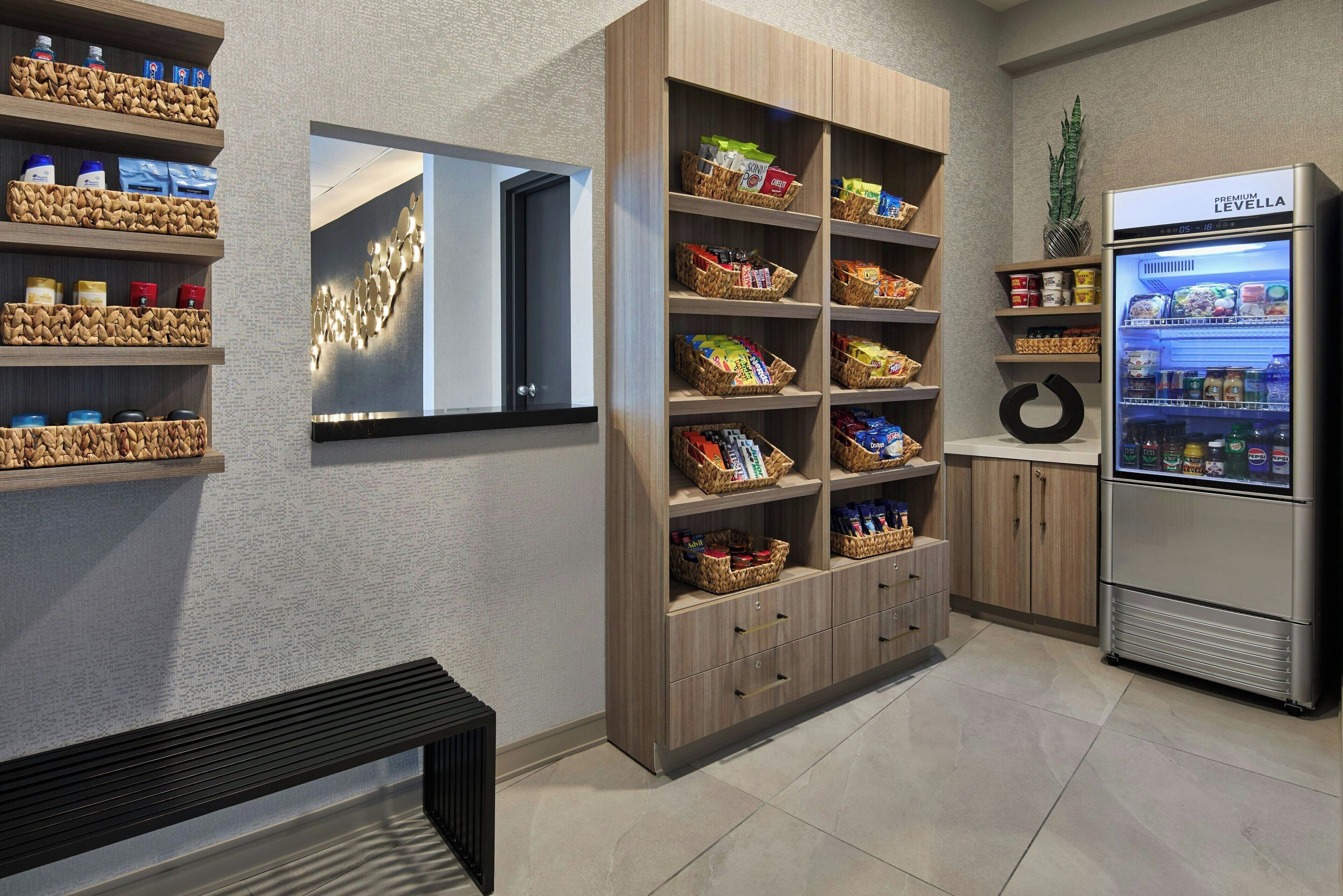 A modern kitchen with wooden cabinets, a built-in refrigerator, and shelves with various food items.