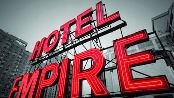 Un neon pubblicitario con la scritta "HOTEL EMPIRE" su uno sfondo di architettura moderna.