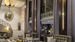 A spacious lobby with a checkered floor, plush seating, and a staircase leading to an upper level.