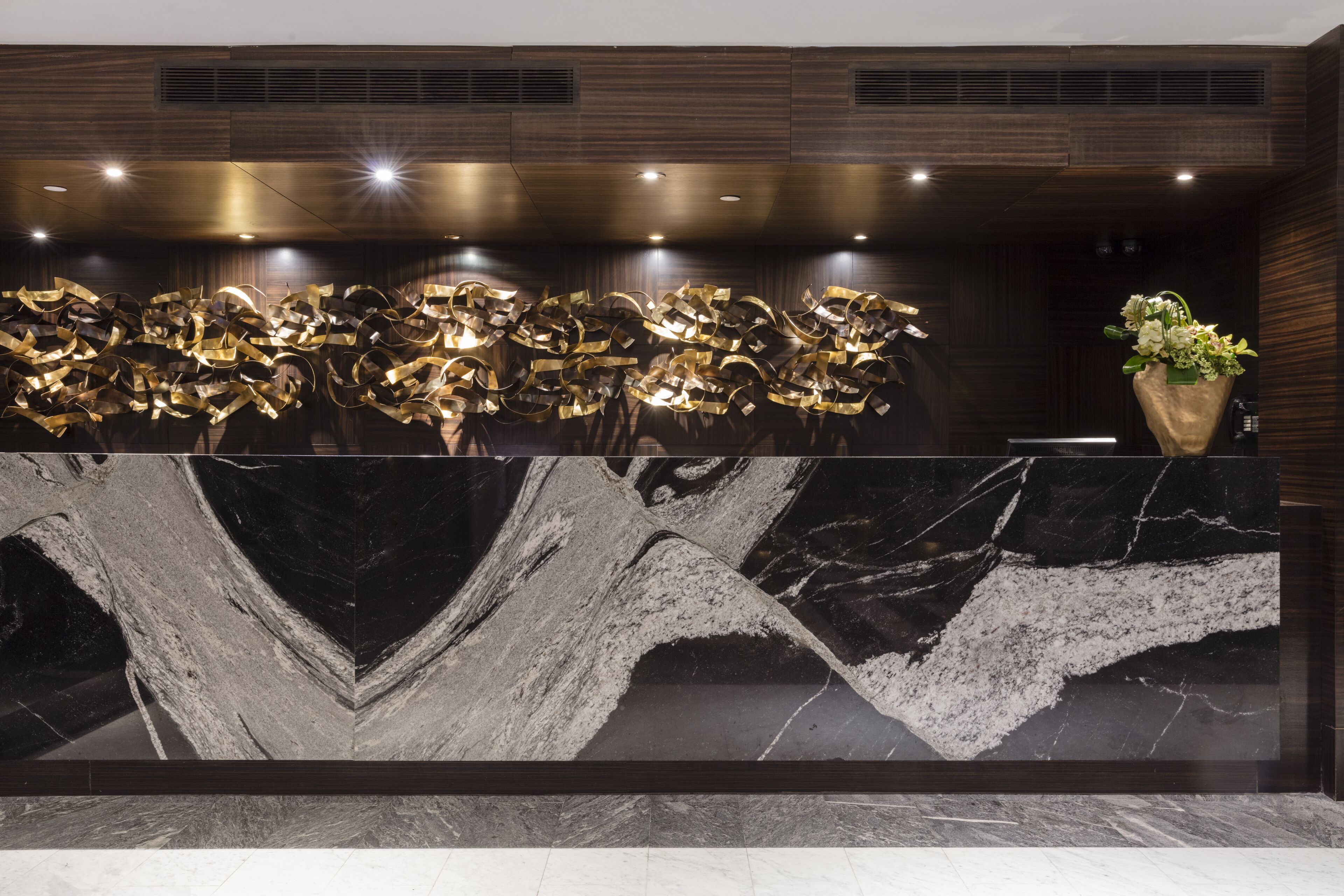 A reception desk with a marble top and a decorative gold sculpture.