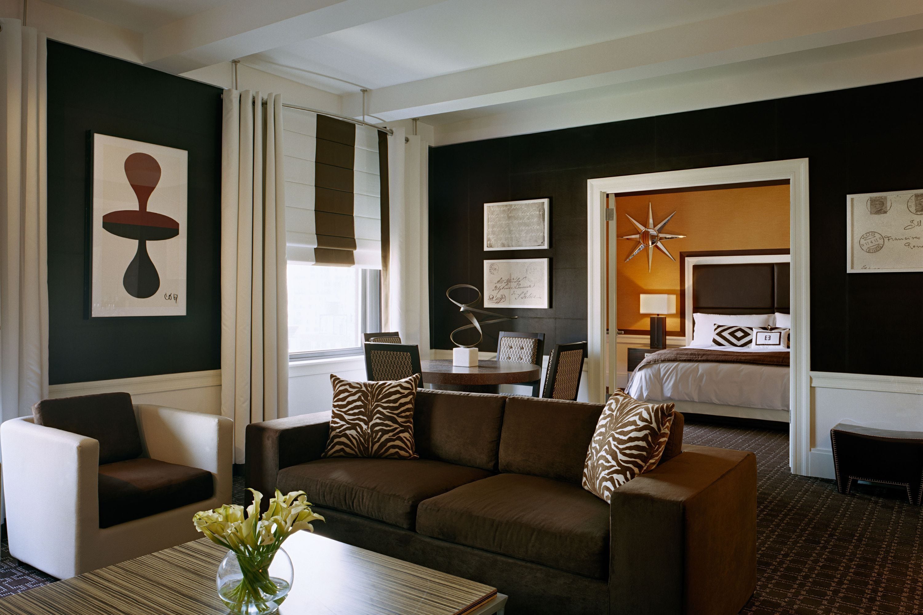 A hotel room with a brown sofa, a dining table, and a bed with a star-shaped decoration.