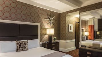 Hotelkamer met een groot bed, nachtkastje met een lamp, een spiegel en een behangen muur.