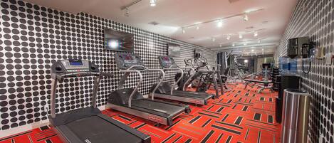 A gym with treadmills, ellipticals, and a red patterned floor.