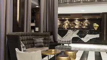 Een moderne lobby met een comfortabele bank, een ronde tafel en een decoratieve wand met een marmer dessin.