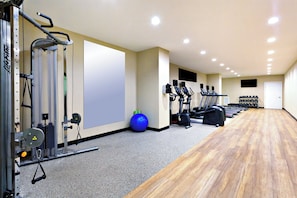 Une salle de sport équipée de machines de cardio, de matériel de musculation et d’un ballon d’exercice bleu.
