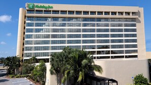 A multi-story hotel building with a flat facade and a green logo at the top. - Holiday Inn Miami West - Airport Area by IHG (Hialeah)