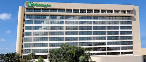 A multi-story hotel building with a flat facade and a green logo at the top.