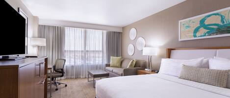 Hotellihuone, jossa on sänky, työpöytä, tuoli ja televisio.