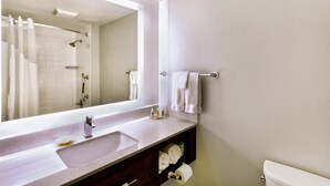 A bathroom with a large mirror, a sink, a toilet, and a shower area. - Holiday Inn Miami West - Airport Area by IHG (Hialeah)