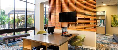 A modern office space with a large desk, two chairs, a flat-screen TV, and a printer.