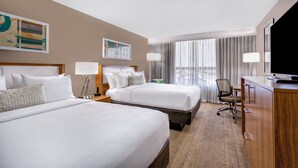 A hotel room with two beds, a desk, a chair, a television, and artwork on the walls. - Holiday Inn Miami West - Airport Area by IHG (Hialeah)