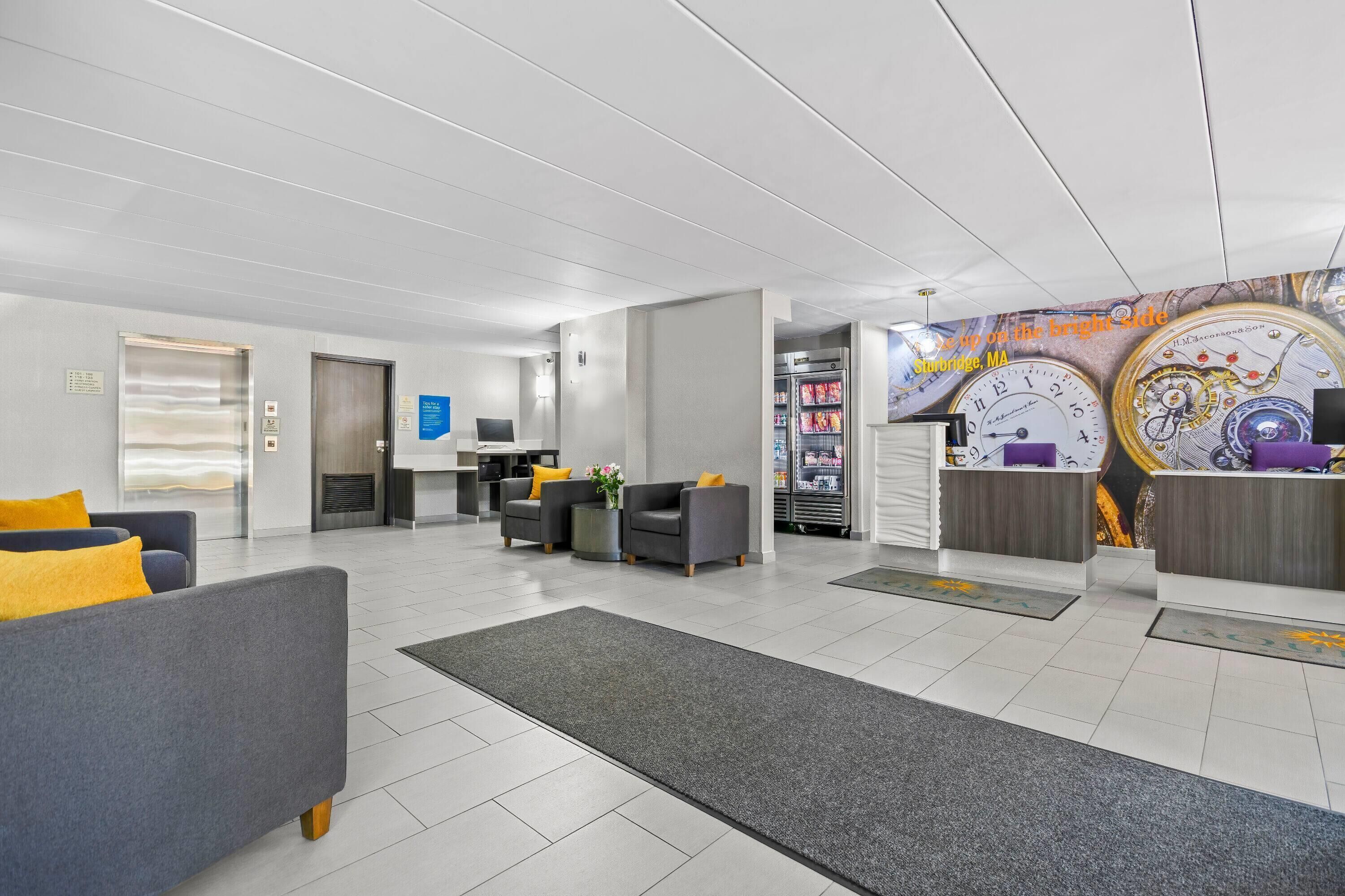A modern lobby with a reception desk, seating area, and a clock mural.