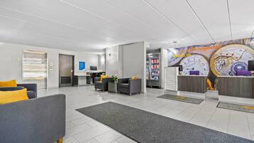 A modern lobby with a reception desk, seating area, and a clock mural.