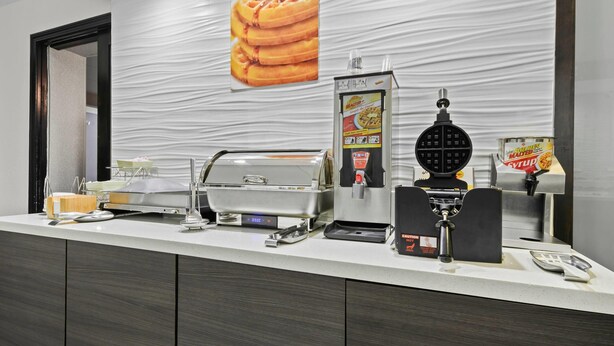 A breakfast bar with waffle makers, syrup dispensers, and a coffee machine. - La Quinta Inn & Suites by Wyndham Sturbridge (Fiskdale)