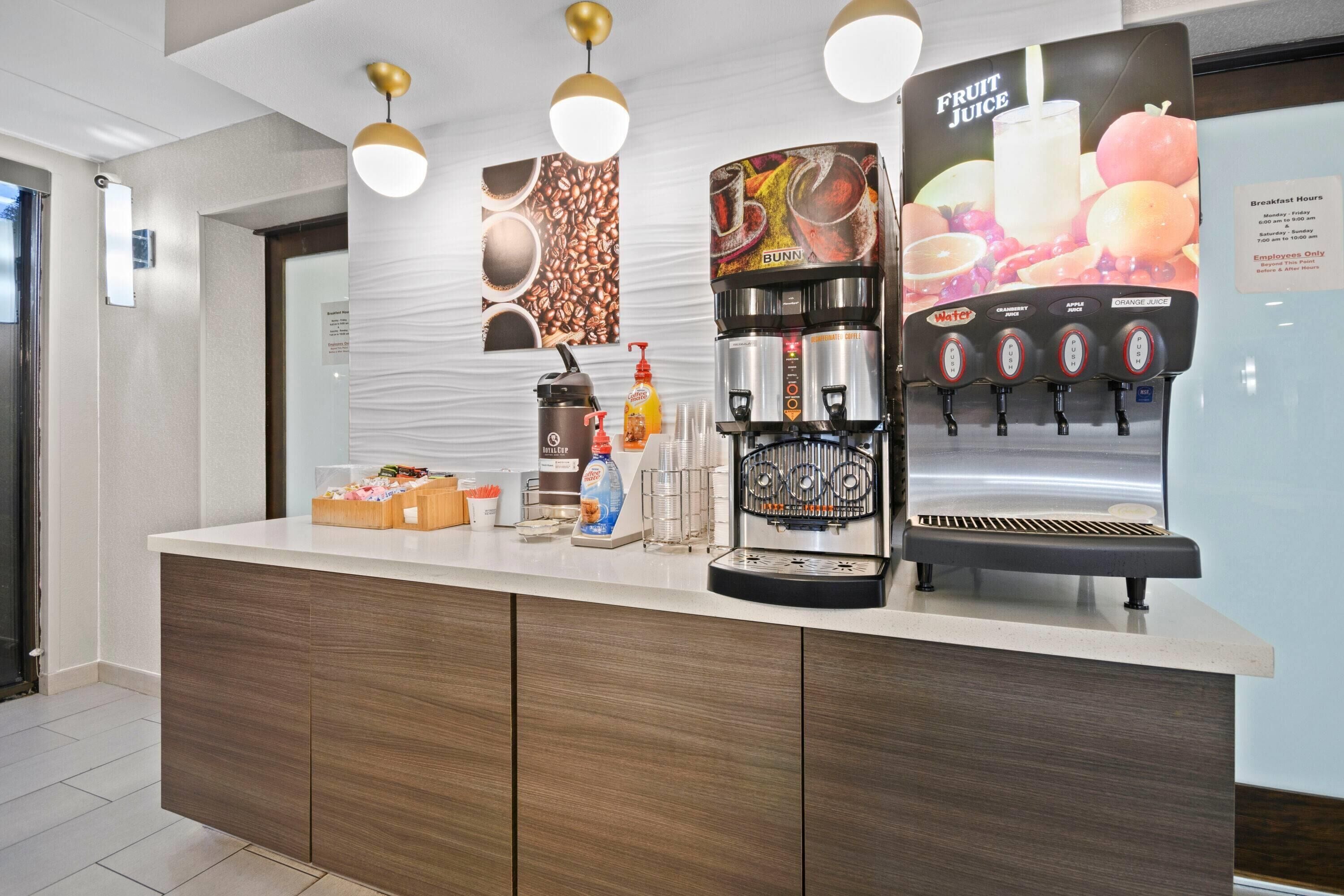 A modern coffee station with a coffee machine, a water dispenser, and a juice dispenser.