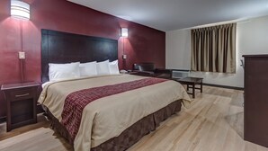 Una habitación de hotel con una cama grande, mesitas de noche, un escritorio y una silla.
