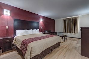 A hotel room with a large bed, bedside tables, a desk, and a chair.