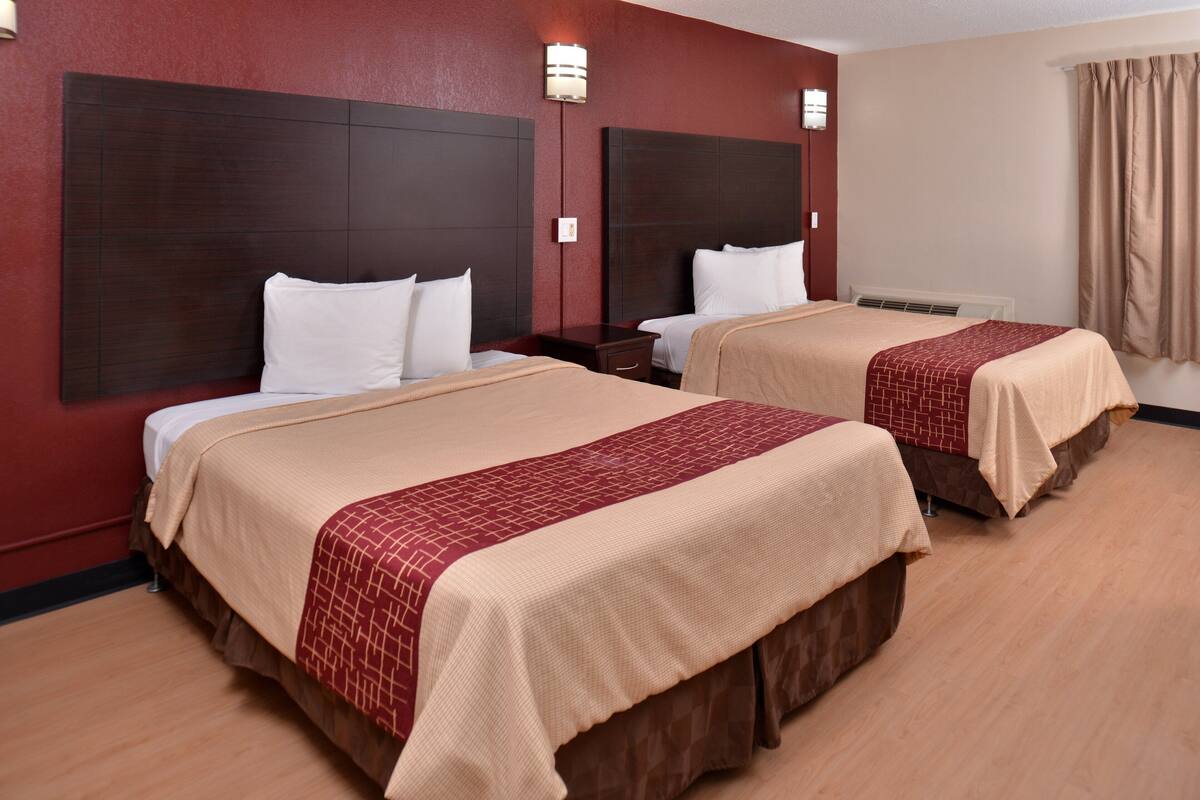 Ein Hotelzimmer mit zwei Betten, dunklen Kopfteilen und Holzboden.