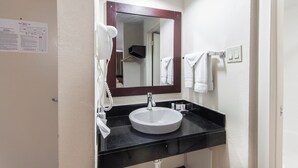 A bathroom with a white sink, a mirror, and a towel rack.