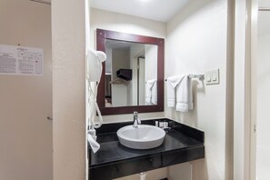 Une salle de bain avec un lavabo blanc, un miroir et un porte-serviettes.