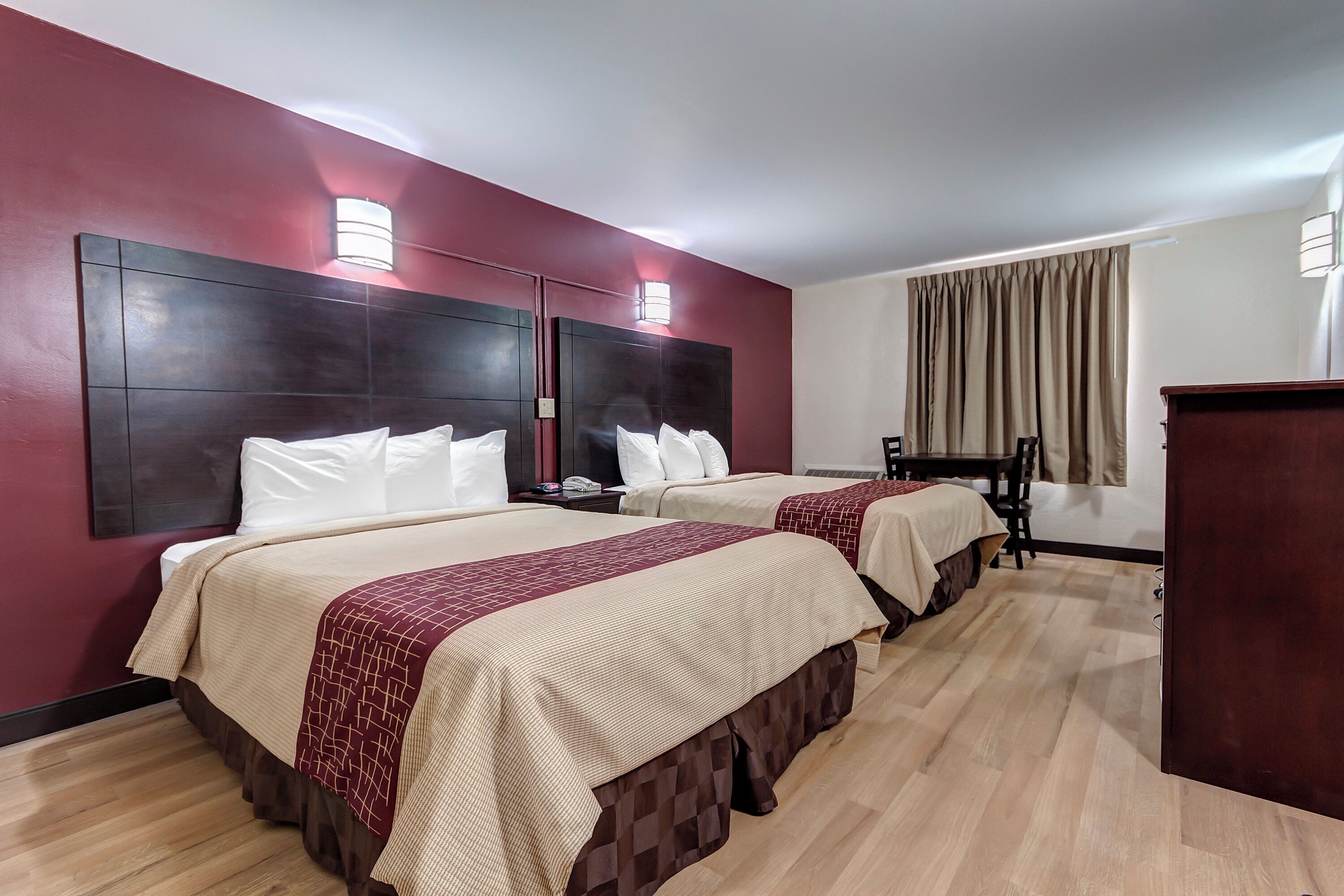 A hotel room with two beds, a desk, and a chair.