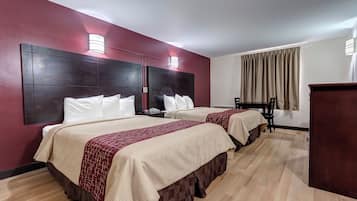 A hotel room with two beds, a desk, and a chair.