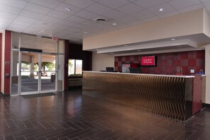 A reception area with a modern design, featuring a check-in counter and an exit sign. - Red Roof Inn Van Horn (Van Horn)