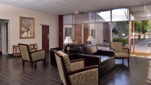 A lobby with a reception desk, seating area, and a large window offering a view of the outdoors.