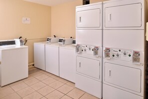 A laundry room with stacked washers and dryers, control panels, and a commercial washer. - Red Roof Inn Van Horn (Van Horn)