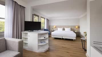 Hotelkamer met een bed, een televisie, een bureau, een stoel en een tafeltje met een lamp.