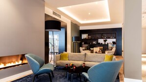 A modern living room with a fireplace, a sofa, two armchairs, and a coffee table. - NH Bussum Jan Tabak (Bussum)