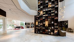 A spacious lobby with a large bookshelf, a piano, and a staircase leading to upper floors. - NH Bussum Jan Tabak (Bussum)