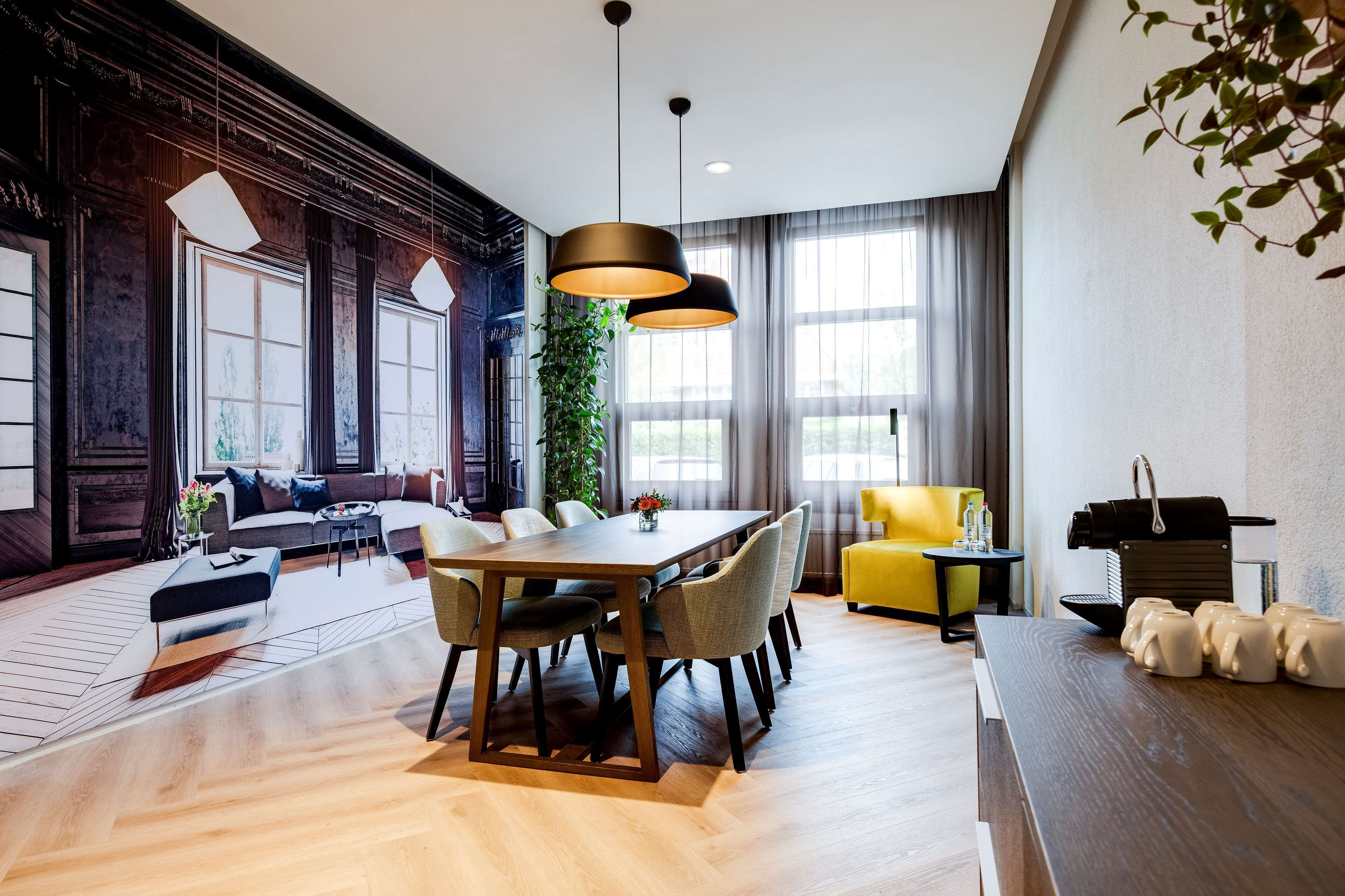 Un salón moderno con una mesa de comedor de madera, asientos cómodos, un ventanal grande y una planta.