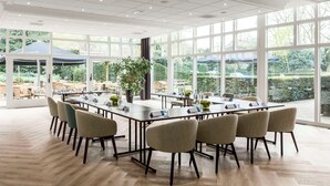 A spacious conference room with large windows, a long table, and several chairs. - NH Bussum Jan Tabak (Bussum)