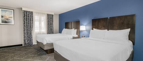 A hotel room with two beds, a large painting on the wall, and a patterned carpet.