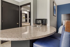 A modern kitchen with a granite countertop, a built-in microwave, and a sink.