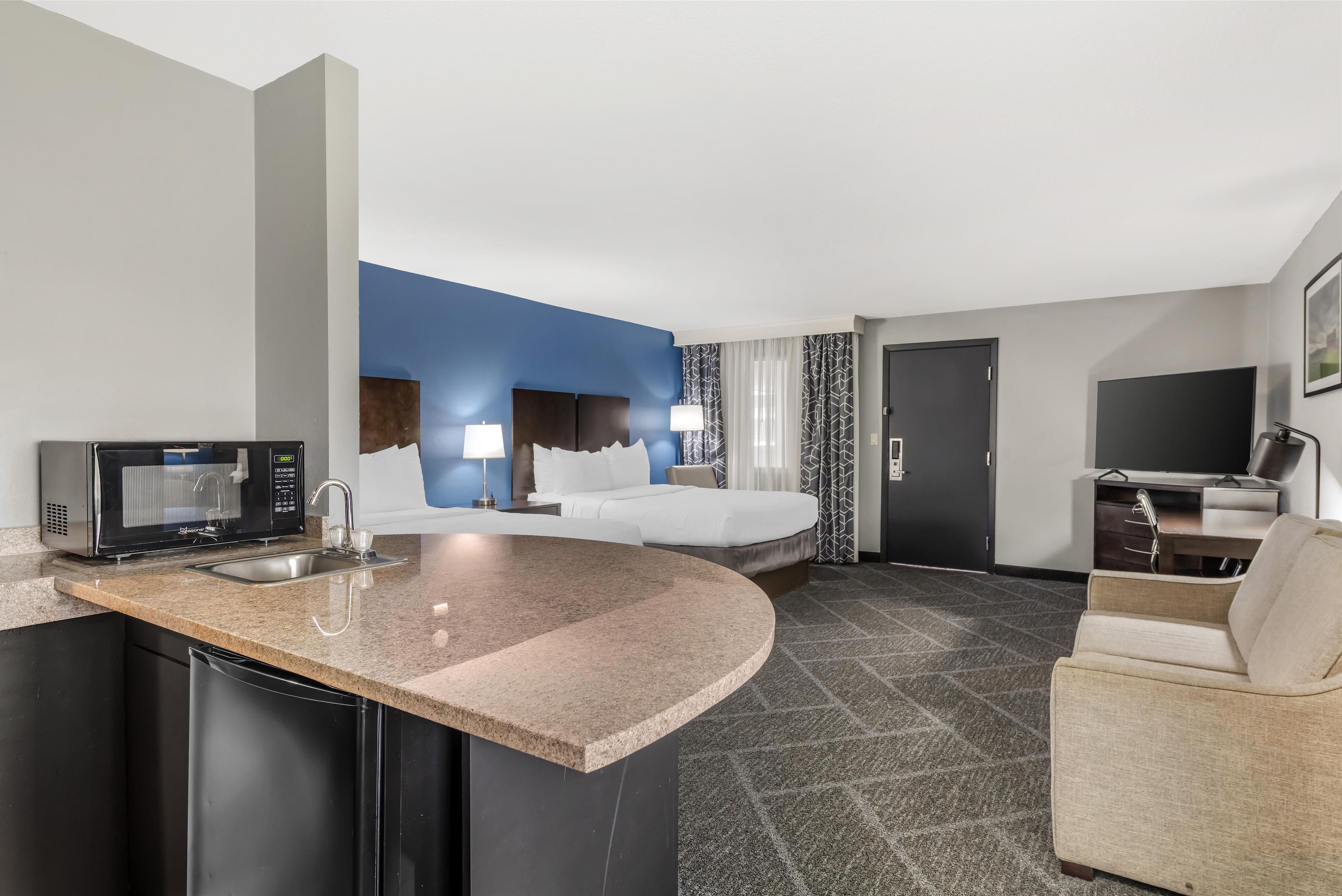 Habitación de hotel con cocina, cama, televisión y zona de estar.