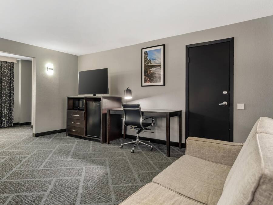 A hotel room with a desk, chair, and a large bed.