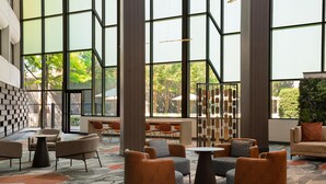 A spacious lobby with large windows, multiple seating areas, and a patterned carpet. - DoubleTree by Hilton Hotel Austin Northwest Arboretum (Austin)