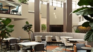 A modern indoor seating area with tables, chairs, and a central sofa. - DoubleTree by Hilton Hotel Austin Northwest Arboretum (Austin)