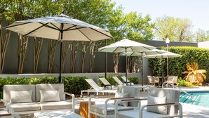 A poolside area with lounge chairs, umbrellas, and a pool. - DoubleTree by Hilton Hotel Austin Northwest Arboretum (Austin)