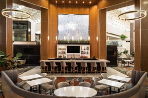 A modern bar area with a central island, bar stools, and seating arrangements. - DoubleTree by Hilton Hotel Austin Northwest Arboretum (Austin)